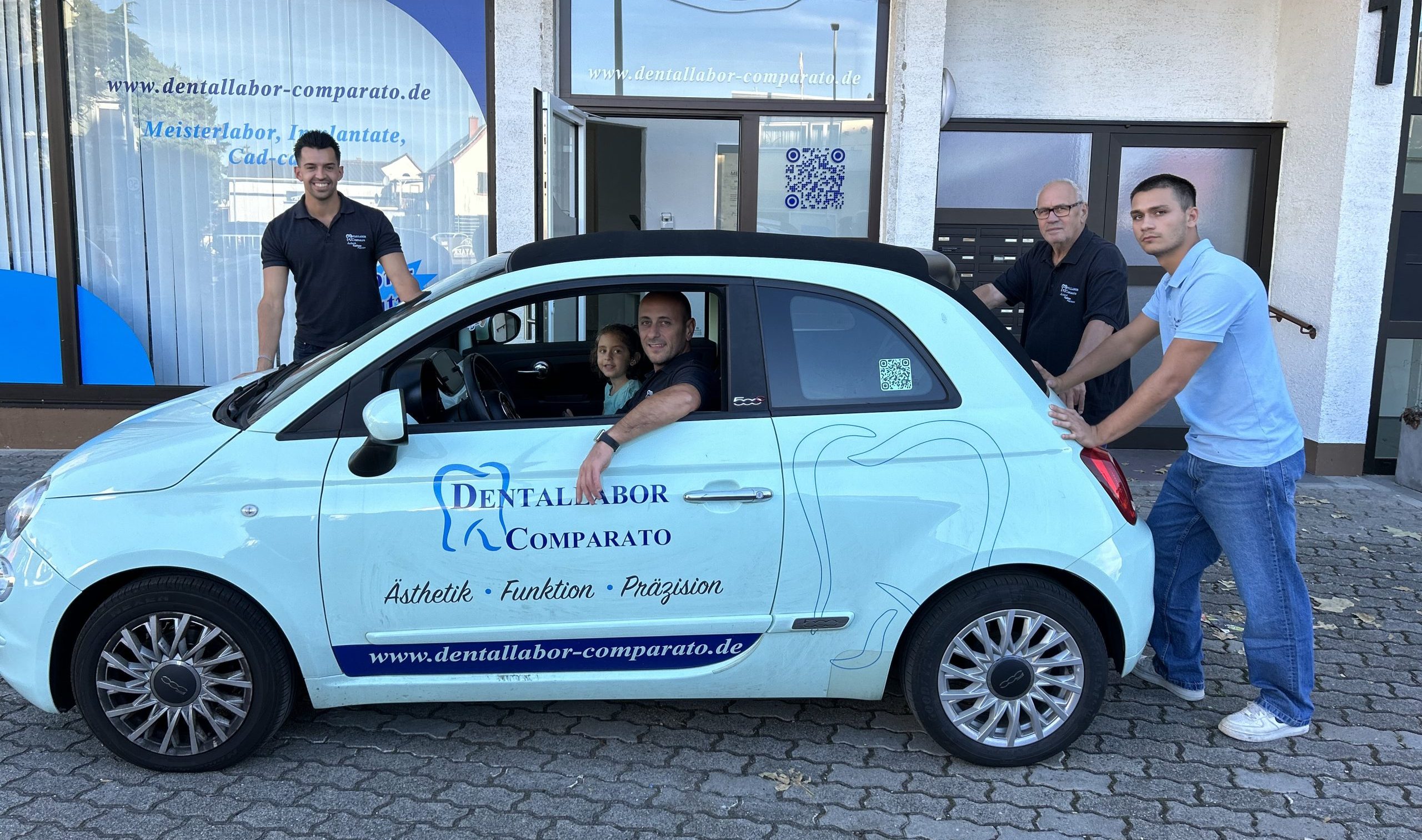 Das Team des Dentallabors Comparato vor dem Labor mit dem hellblauen Firmenauto